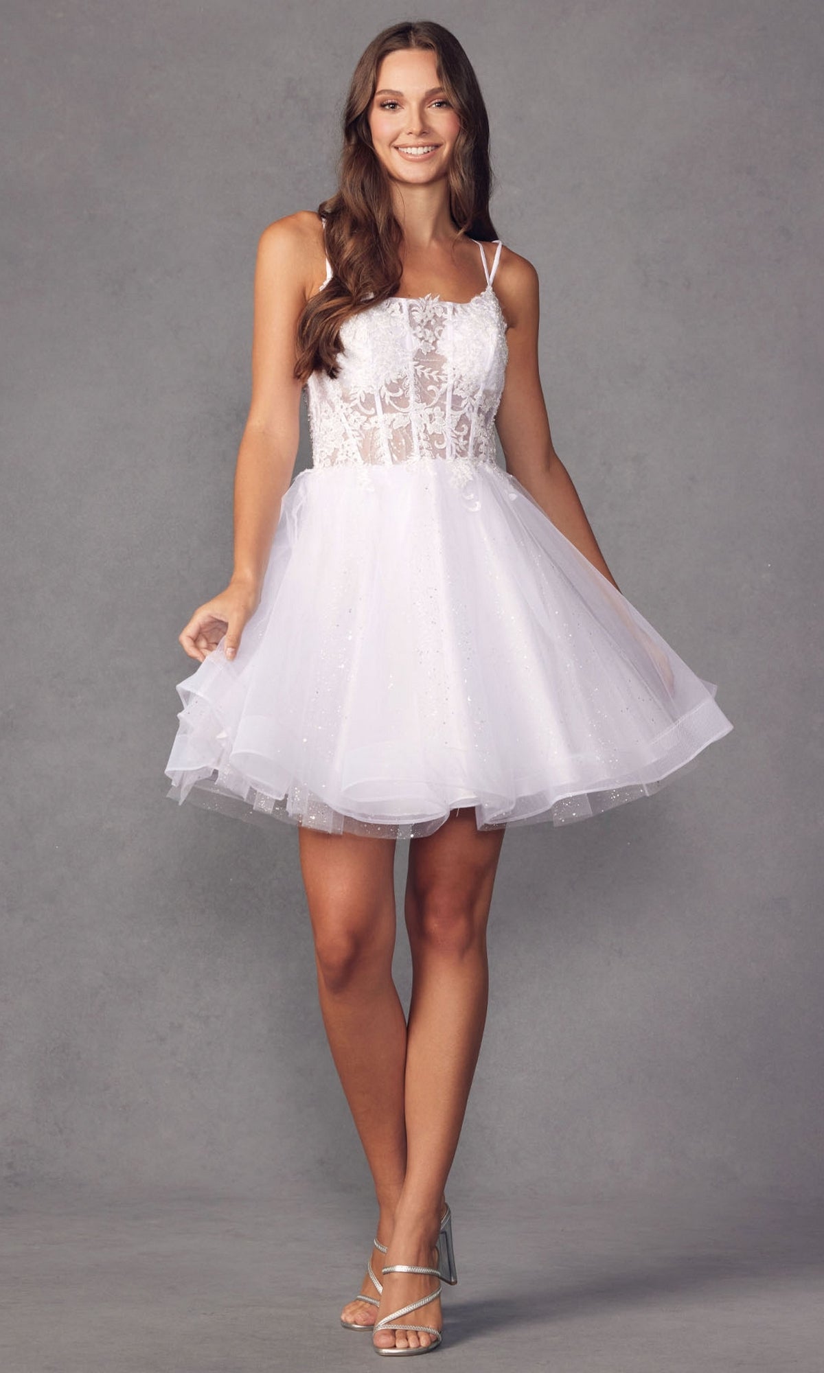 A woman models the Sheer-Bodice Short A-Line Prom Dress 883, featuring a sleeveless white corset-style bodice and tulle skirt, paired with strappy heels against a gray background.